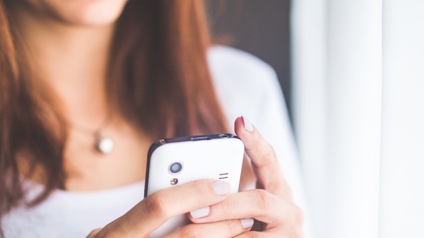 Med thumb close up portrait of a young woman typing a text message on mobile phone